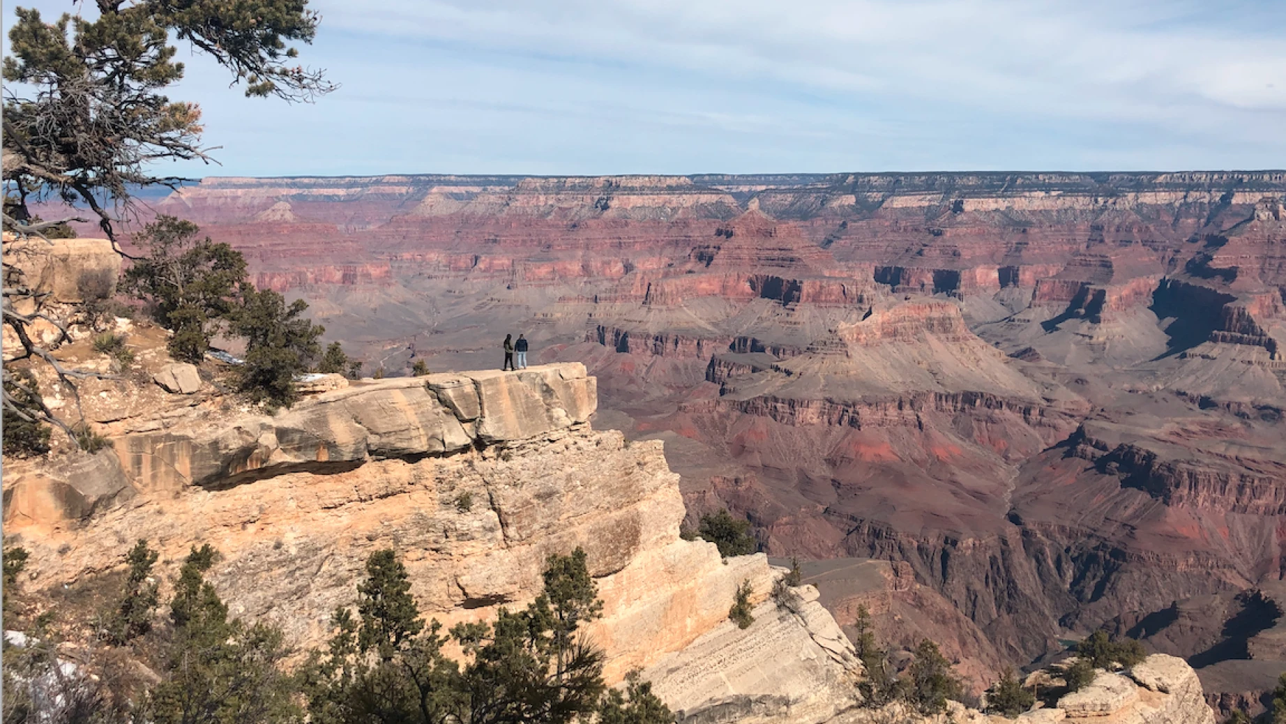 Twee mensen staan aan de rand van een krater en kijken uit over de Grand Canyon in Arizona.