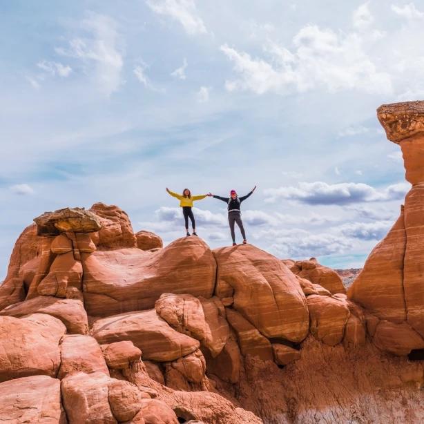 Twee mensen houden hun armen in de arm terwijl ze bovenop rotsen staan in Kanab, Utah