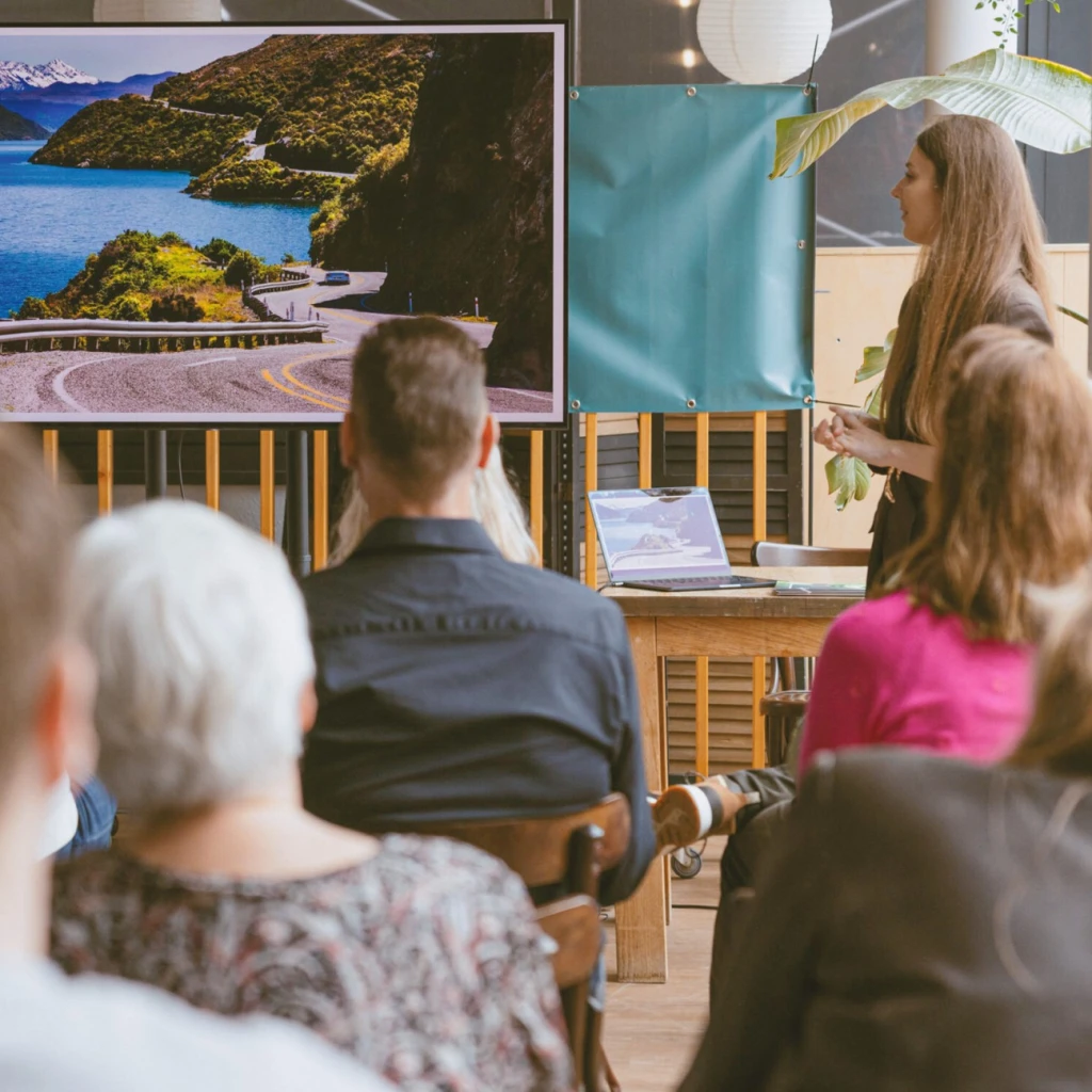 De reisexpert van TravelEssence geeft een presentatie over een land in een zaal vol mensen.