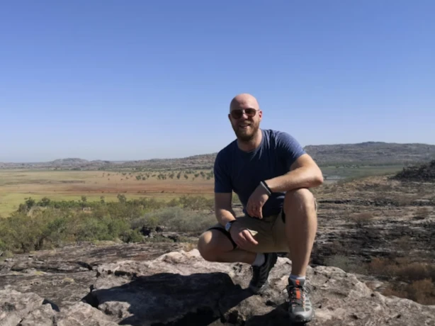 Bart glimlacht naar de camera met een uitzicht op de achtergrond