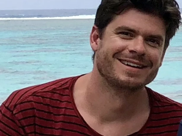 Hendrik-Jan lacht naar de camera met de oceaan op de achtergrond