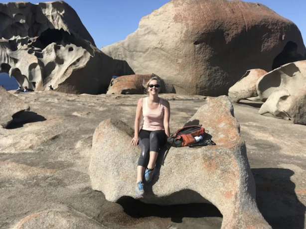 Ilona zittend op een rots, lachend naar de camera