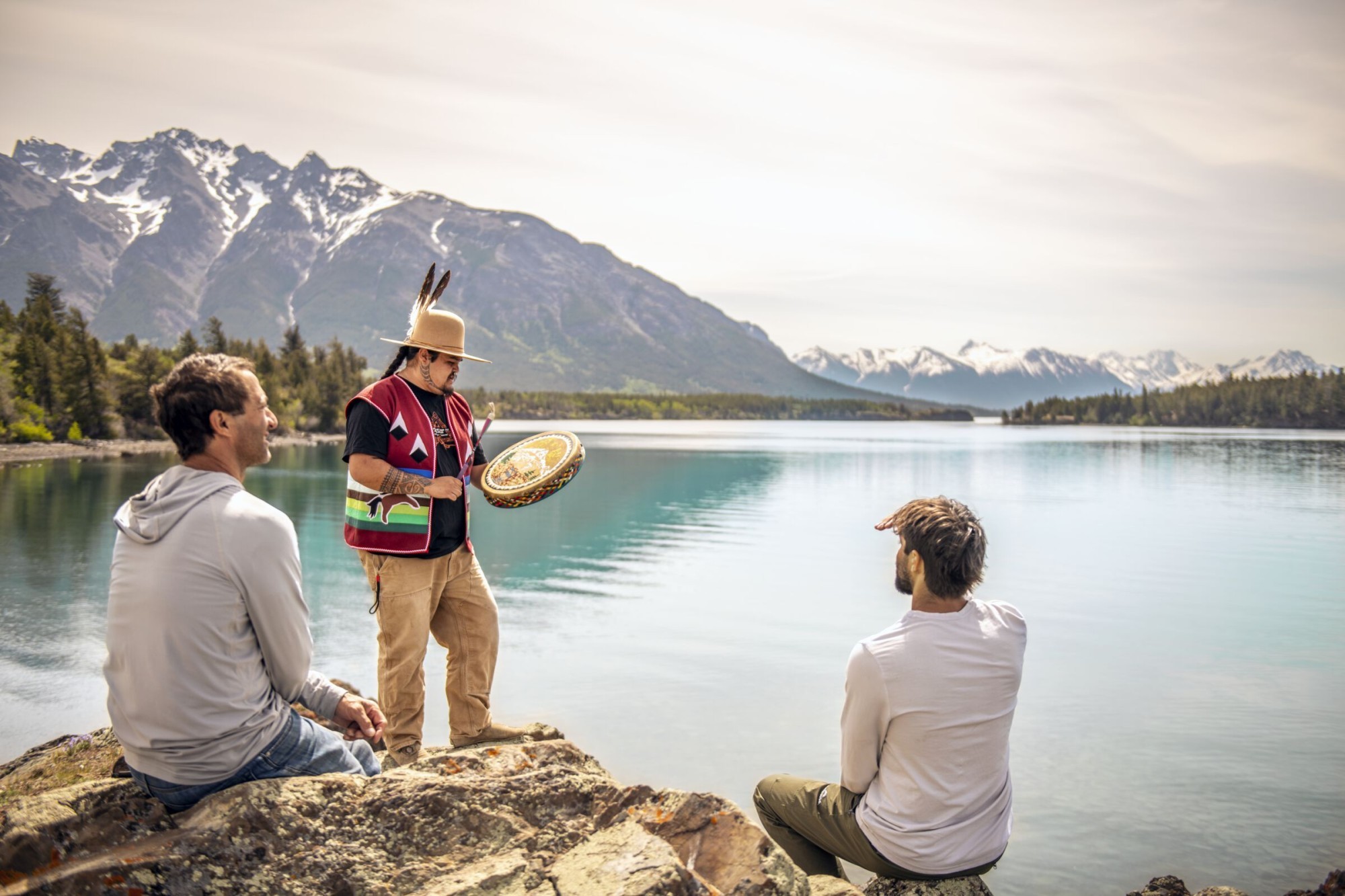 Een vader en zoon kijken naar een drumceremonie uitgevoerd door een inheemse gids bij Chilko Lake in British Columbia, Canada.