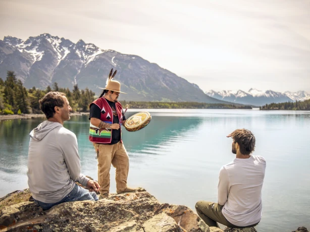 Een vader en zoon kijken naar een drumceremonie uitgevoerd door een inheemse gids bij Chilko Lake in British Columbia, Canada.