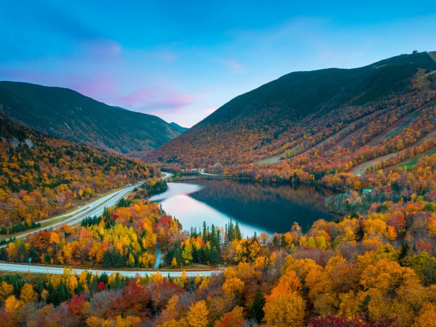 Herfstbladeren rond een meer en een weg in New England, VS
