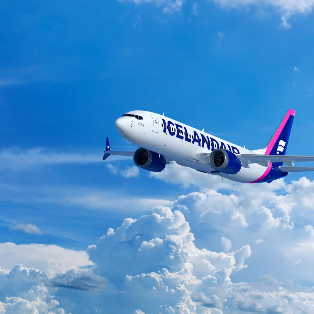 Een vliegtuig van Icelandair vliegt boven helderwitte wolken tegen een strakblauwe lucht.