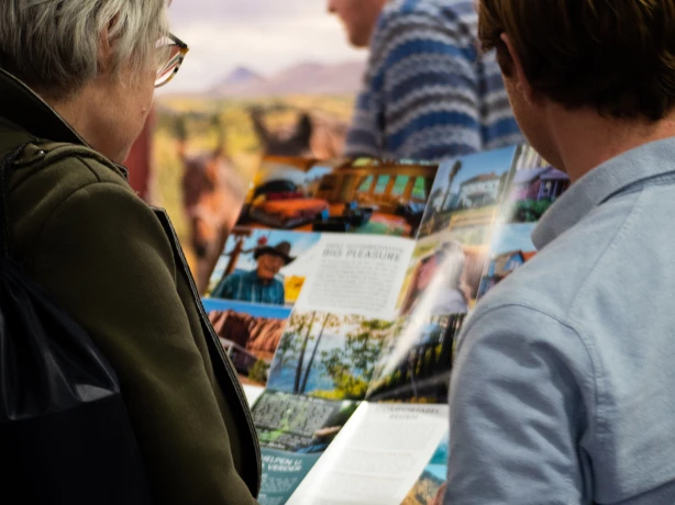 Twee mensen lezen een brochure van Little America om hun reis naar Noord-Amerika te plannen.