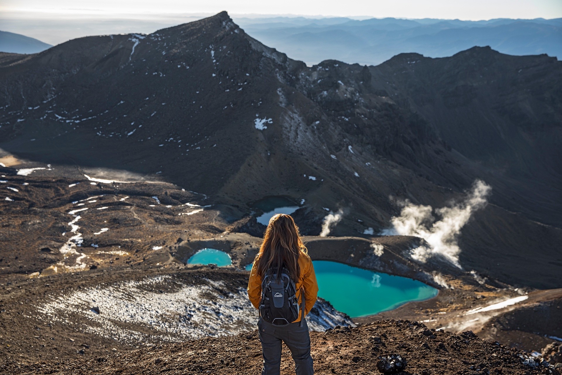 Een vrouw met een rugzak kijkt uit over de vallei in het Tongariro National Park in Nieuw-Zeeland