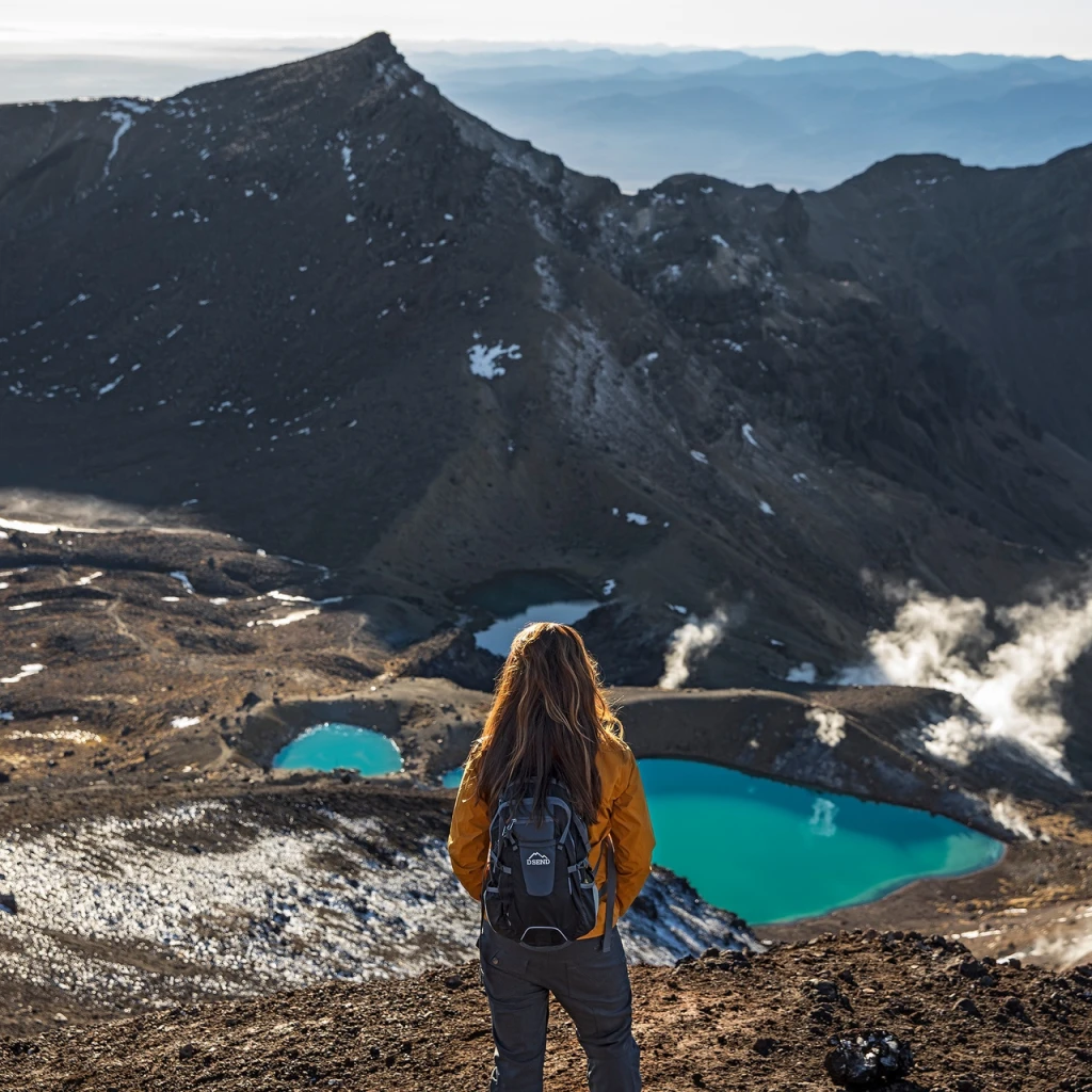 Een vrouw met een rugzak kijkt uit over de vallei in het Tongariro National Park in Nieuw-Zeeland