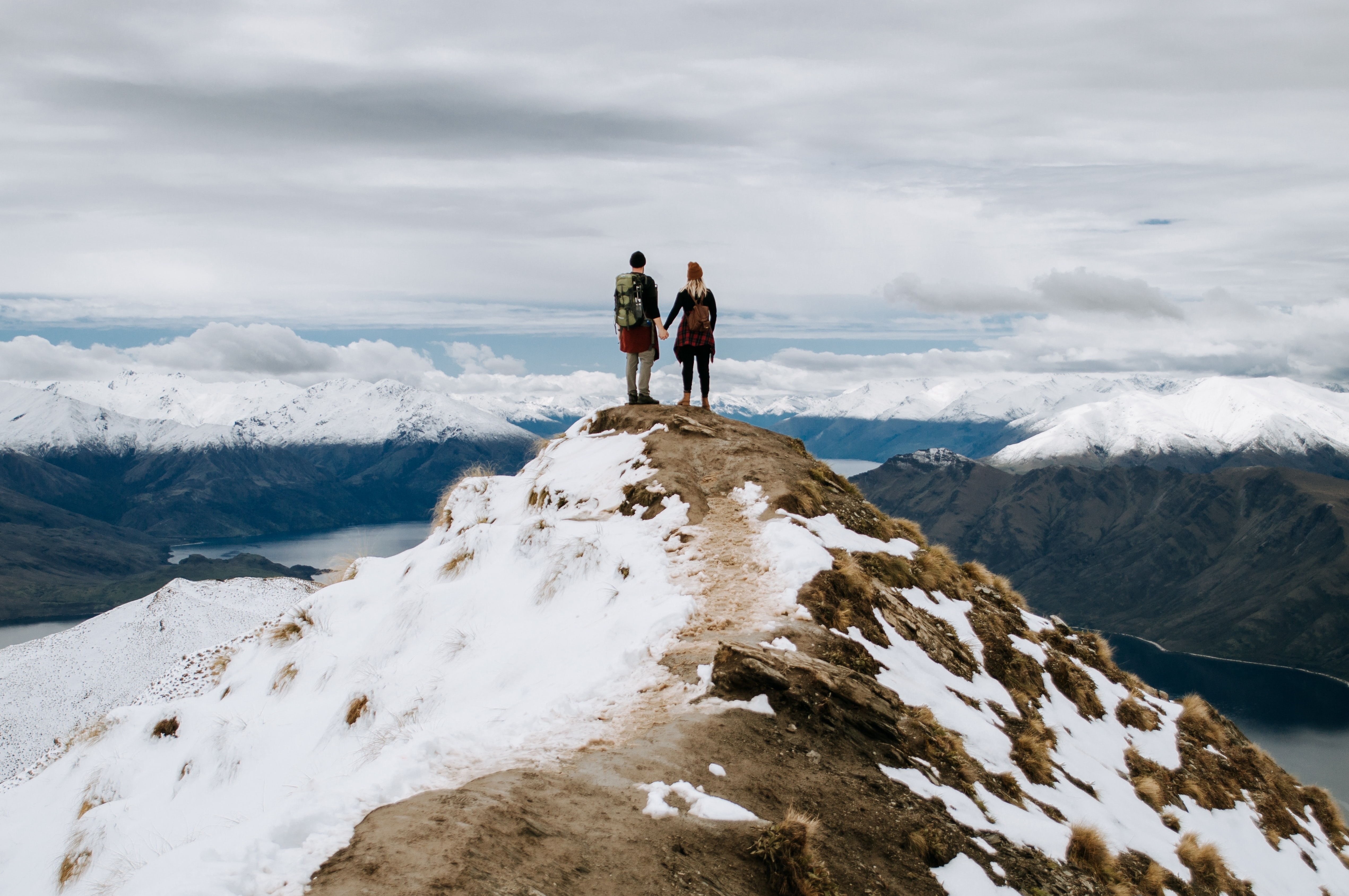 Paar staat op bergtop uitkijkend over bergtoppen en fjorden