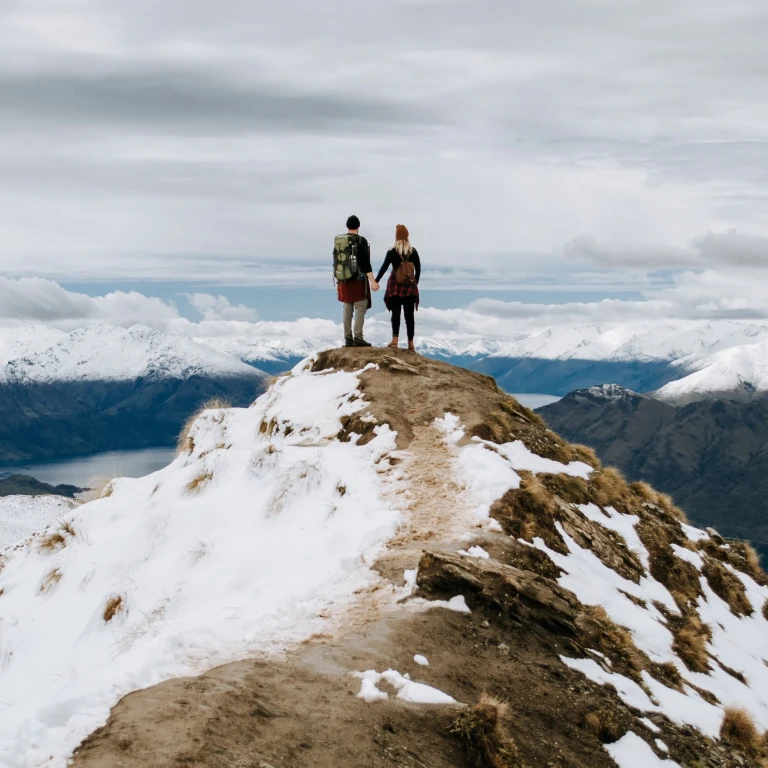 Paar staat op bergtop uitkijkend over bergtoppen en fjorden
