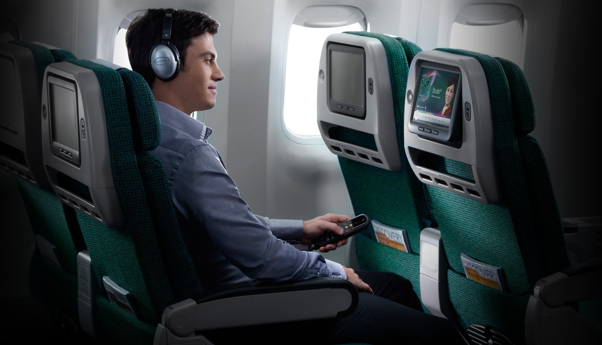 Een man geniet van het entertainment aan boord in Premium Economy op een vlucht van Cathay Pacific