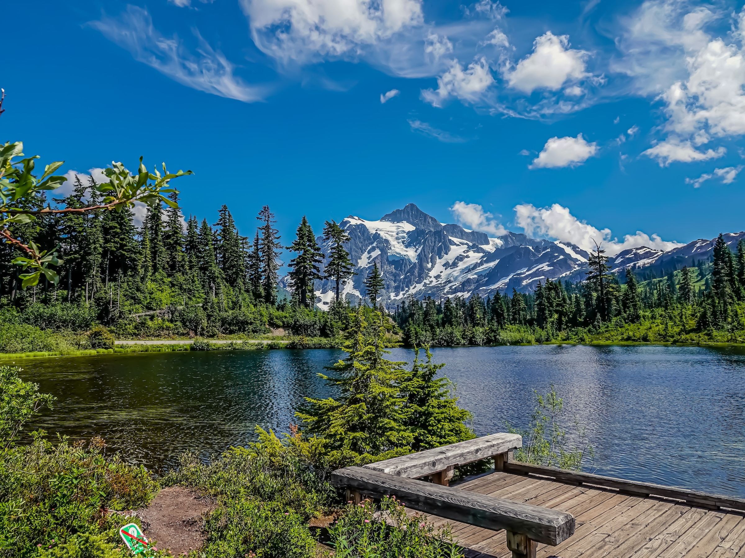 Een vredig meer in het Mount Baker-Snoqualmie National Forest in Washington, met dichte evergreens en besneeuwde bergtoppen op de achtergrond.