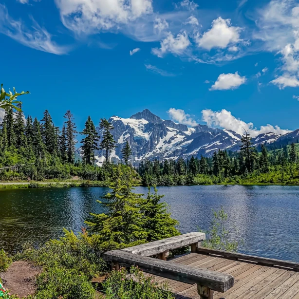 Een vredig meer in het Mount Baker-Snoqualmie National Forest in Washington, met dichte evergreens en besneeuwde bergtoppen op de achtergrond.